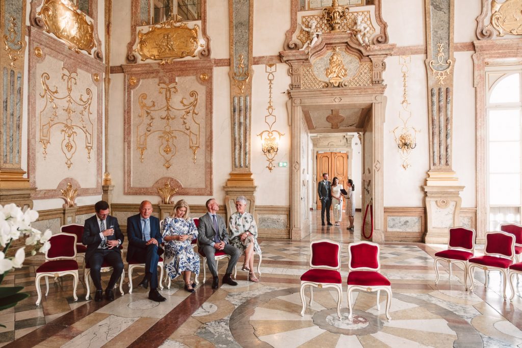 Die Familie wartet auf das Brautpaar sitzend im Saal.