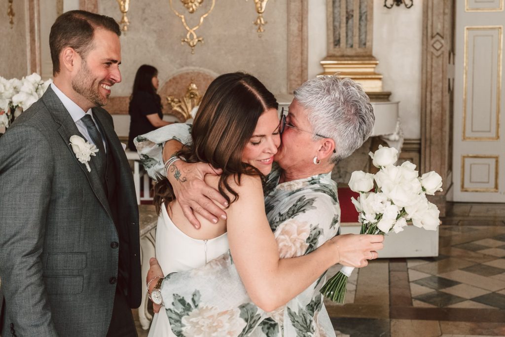 Die Brautmutter küsst die Braut auf die Wange und gratuliert.