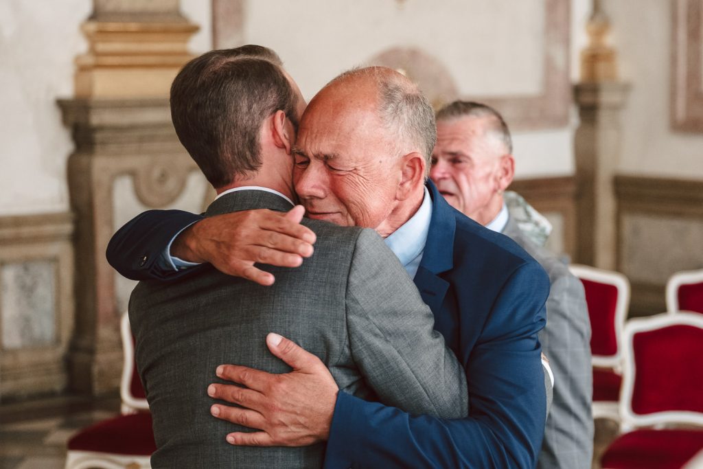 Emotionen bei der Gratulation. Der Vater weint in den Armen des Bräutigams.